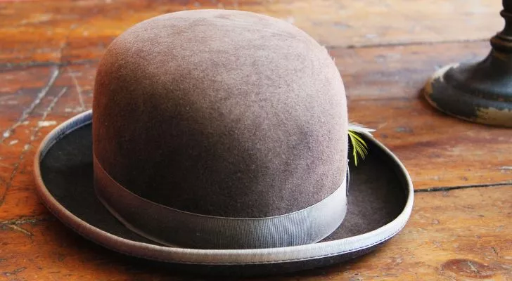 An old British bowler hat laying on a wooden table